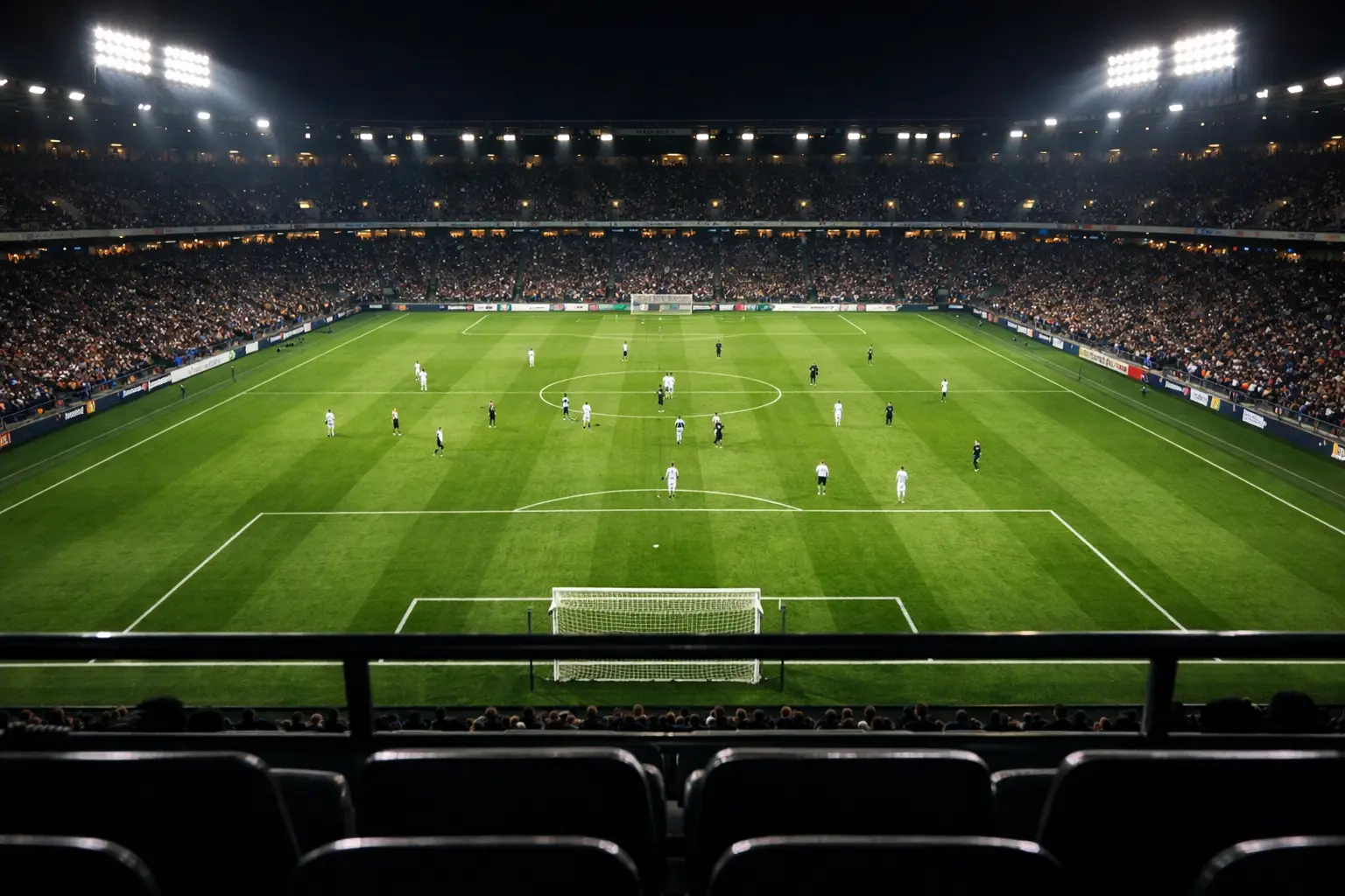 Konzentrierter Blick aus der Tribüne auf das Fußballspielfeld bei Flutlicht